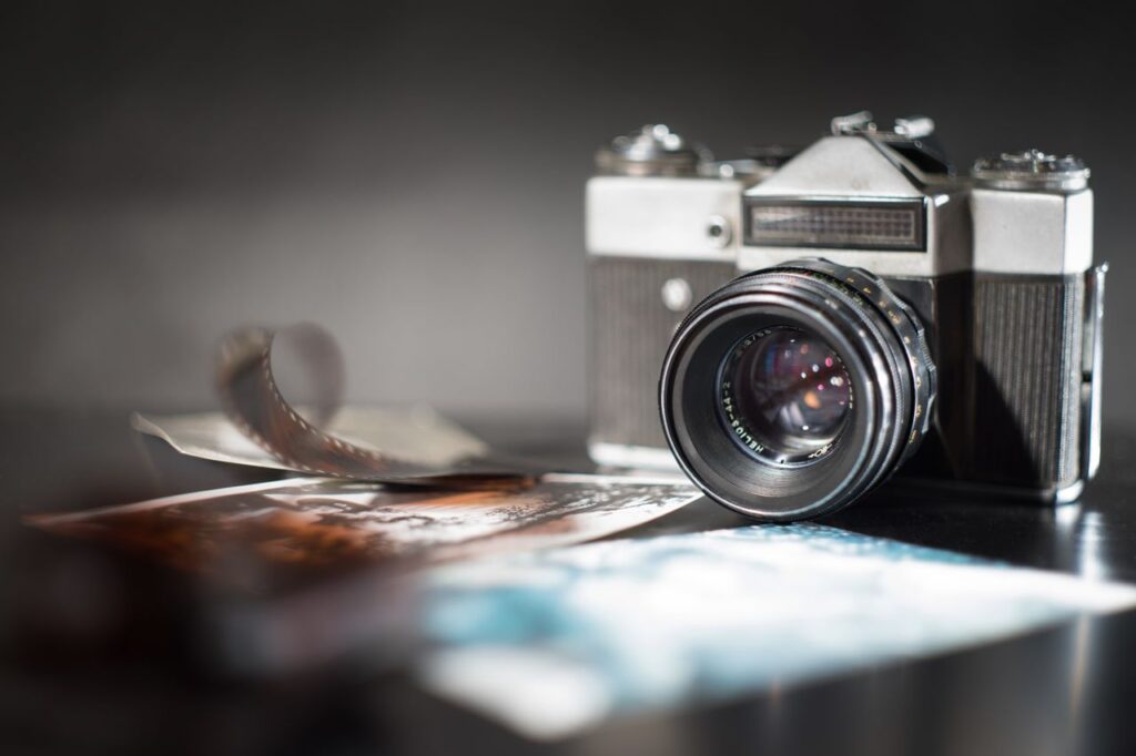 A vintage camera with a blurred film strip and photographs, creating a nostalgic feel.